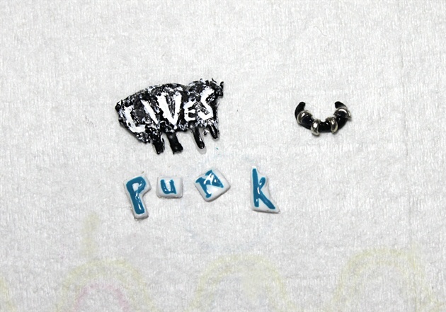 Using Shellac, paint the letters PUNK in both upper and lower case. For the LIVES, use a paint spatter/graffiti style. Use more pieces of cut wire to add embellishments to the rocker's choker.
