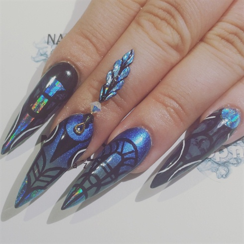 After applying more foil to the nails, I started going in with line work inspired by a beautiful haute couture dress with black and white acrylic paint. Using nail adhesive, I attatched the feather that is connected to gold wire.