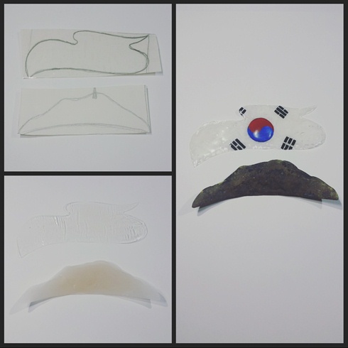 I started with pieces of paper with outlines of the Hamsan Mountain and a Korean flag cloud. I then double sided the paper with clear take for a slick finish to sculpt on.\n\nI layered gel top coat 3 times, curing between each coat. Then I cut the edges with small scissors for a clean edge. I then swirled white gel polish and gel top coat for a cloudy effect, leaving clear spots, but keeping true to the flag and having it predominantly white. I then used blue and red gel polish to create the center of the flag, and then I used black acrylic paint to paint on the trigrams. To make the center look bubbly, I added 3 layers of hard gel, curing between each coat, and then topping the entire piece with gel top coat and curing.\n\nFor the mountain, I used several dry balls of acrylic to create a rough texture for the country side. I then sponged on green, black, and brown acrylic paint and topped it off with matte top coat.