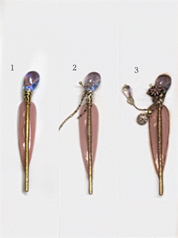 1. Attach hairpin to nail with Bling On, cure.\n2. Insert headpin into wire and attach two gold chains to the wire with Bling On, cure.\n3. Connect beads and squares with Bling On, and outline the perimeter of the nail with Golden Nugget, cure. Topcoat with Shine On, cure.