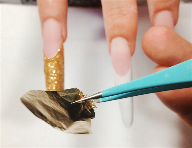 Apply chunky gold glitter gel on the thumb and ring finger. After curing, place gold foil leaf over the sticky gel. The chunky glitter leaves a textured, semi 3D, feel and appearance.