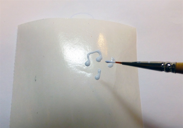 Paint music notes with white sculpting gel on wax paper, cure and attach to ring finger.