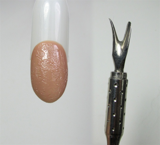 Prep your nails for gel polish application. Apply first coat of nude polish and cure. For second coat of polish cure halfway so it is still moveable. Use the end of a cuticle pusher to make some scratches and dents on the surface. This will give your nails the texture of an old book. Cure polish fully.\n