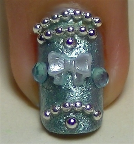 In the middle of the nail, place a cute 3D pearl bow and 2 rhinestones on the sides with clear polish