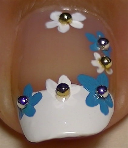 Add clear polish over the light blue flowers center and apply silver beads
