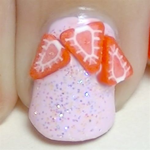 While the glitter nail polish is still wet, I'm using it as glue for these cute strawberry fimo slices. \n\nAdd a mega shine top coat to protect your manicure and specially to secure the fimo decoractions in place and that's it! :)