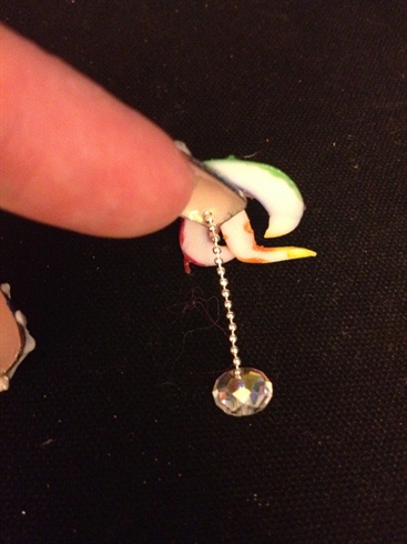Glue a short piece of ball chain to a round crystal. Place a drop of glue on the other end of the chain and feed the end through the drilled hole.  Wait a few moments for the glue to dry.