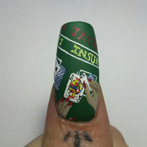 I painted cards and hands on the nail using acrylic paint. I went in with a small striping brush and painted in the detail of the cards. I painted on the words that are on a black jack table. I top coated the nail with a matte top coat.