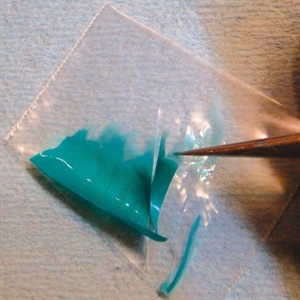 After the gel polish is removed from the lamp use scissors to cut the plastic coated with the gel into different shapes. Cut your shapes so that the edges are easy to separate from the plastic as shown.
