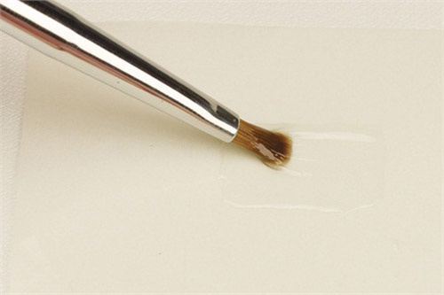 On wax paper, or paper from a nail form, apply a very thin, even layer of flexible clear gel (Bio Sculpture Clear Gel). Fan the bristles and paint in every direction to ensure a perfectly even layer of gel. Cure for 30 seconds under a UV light. Make sure your sheet is at least 1/2-in. by 1/2-in.