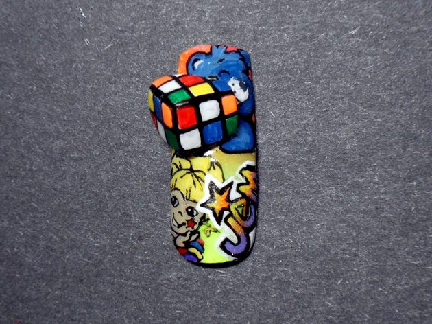 Place the Ribik's Cube on the finished nail, and secure with glue. Bring the nail to a high shine with a gel top coat!\n\nVOILA! Now Baby Tug is holding the Rubik's Cube!!