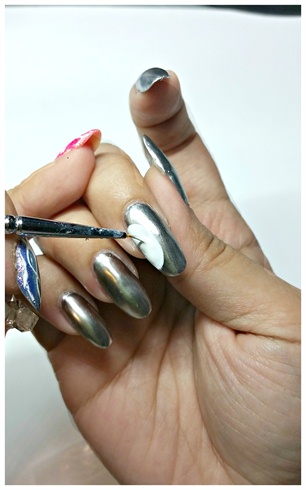 We start this design by shaping the nails round to match the cover and painting all 5 fingers with a chrome silver polish as base. Having the silver as base creates the mirror effect in many stained glass pieces.\n\nProceed to colour in two half circles with white gel paint in the middle and index fingers.