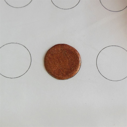 Printed out a sheet of paper with different size circles and placed this in a plastic sheet to use as a guideline.\nPick up a large bead of powder and place it in the center of the circle. Press out to create a perfect circle, ensuring the circle is even all way round.\n