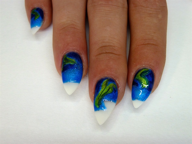 I began my northern lights nails with two shades of blue gel polish and three greens. I have used a medium and dark blue and a deep emerald green and bright green along with a teal shade. This design works best with shimmer finish gel polishes. Using a thin gel brush, I applied the Aurora formation using all three greens side by side then filled the remaining night sky in, adding the lighter blue directly around the greens and close to the 'ground' of my design.
